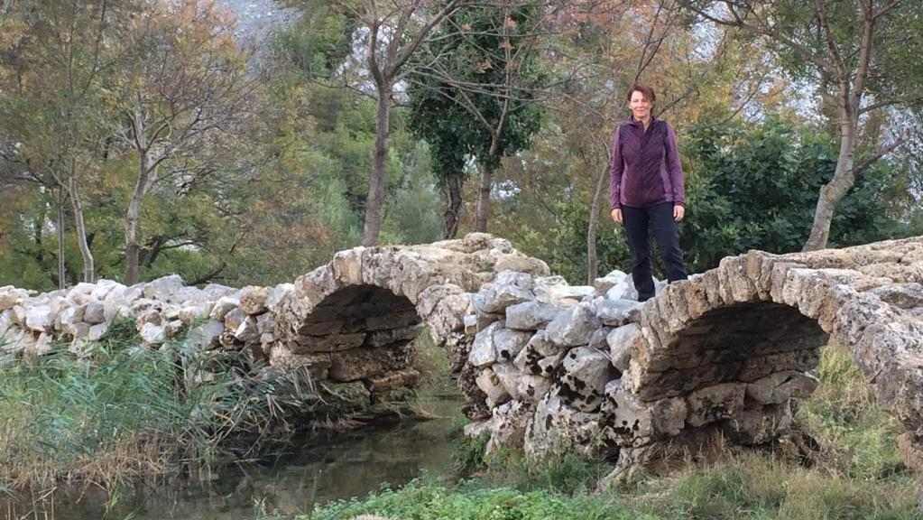 Wandelvrouw staat op de brug van Kude over de rivier van Krupa