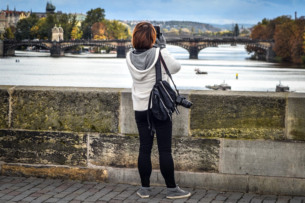 Stedentrip Praag jonge vrouw fotografeert brug Praag