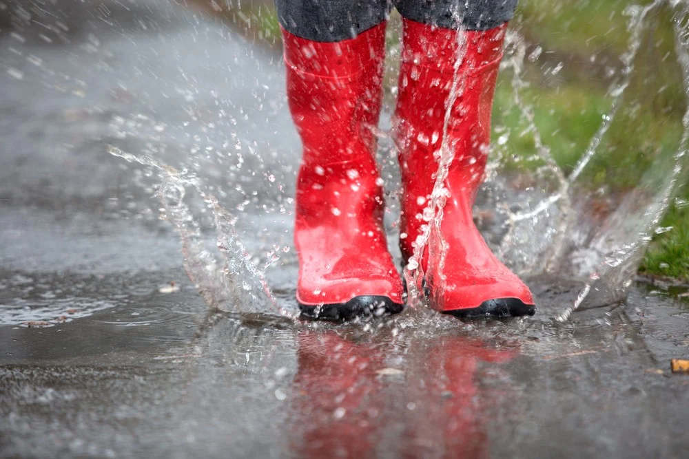 rode rubberen laarzen in waterplas - hooikoorts wandelen na regen